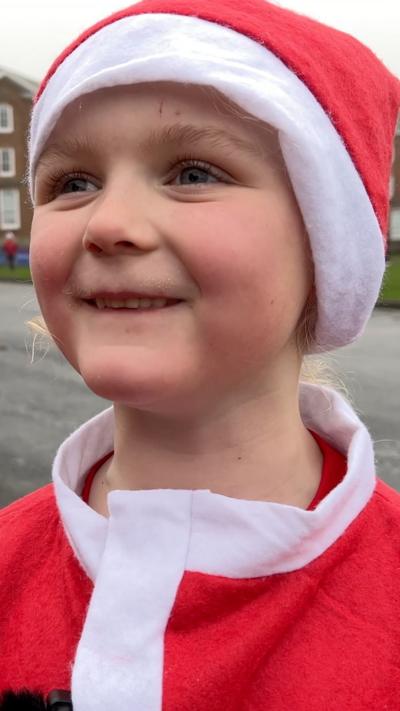 Child in Santa costume smiles at camera