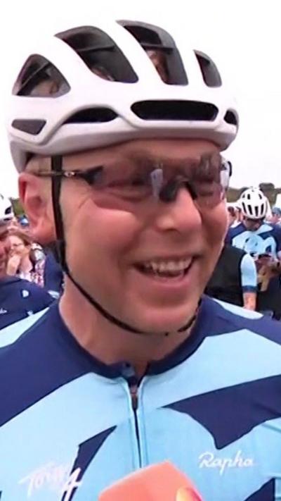 Sir Chris Hoy dressed in cycling gear, smiling and surrounded by other cyclists