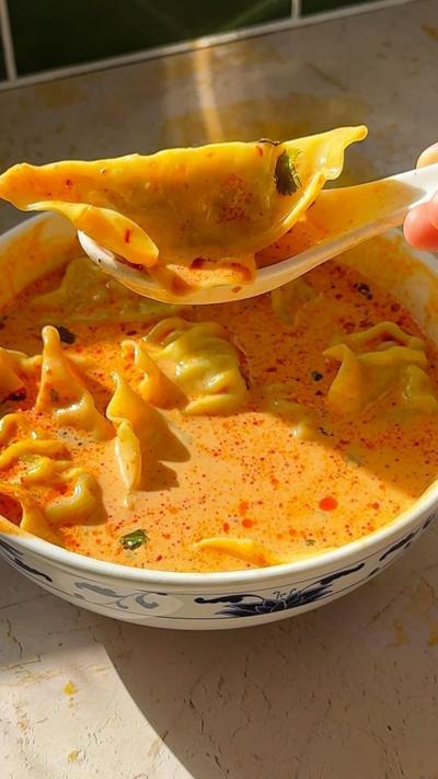 Coconut curry dumpling soup in a white bowl.