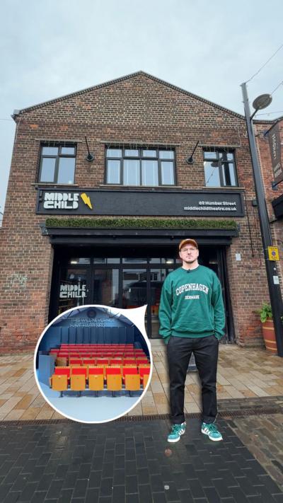 The image shows Paul Smith standing in front of a brick building with large glass doors and windows. Above the entrance is a sign that reads “MIDDLE CHILD” with a yellow lightning bolt symbol, along with the address “69 Humber Street” and the website “middlechildtheatre.co.uk.”