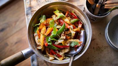 Top down view of stir fry jalfrezi in a wooden handled pan