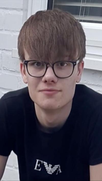 Teenager with dark hair and glasses wearing black t-shirt 