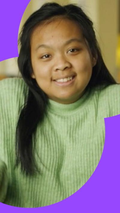 Woman looking at camera with long black hair and a green jumper