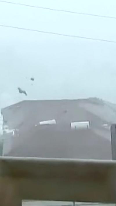 Roof tiles are seen flying in the air above a red tile roof in Montego Bay