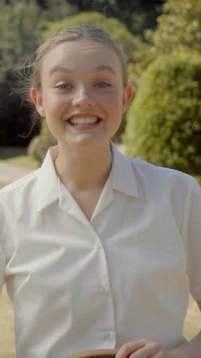 A young girl smiles enthusiastically.