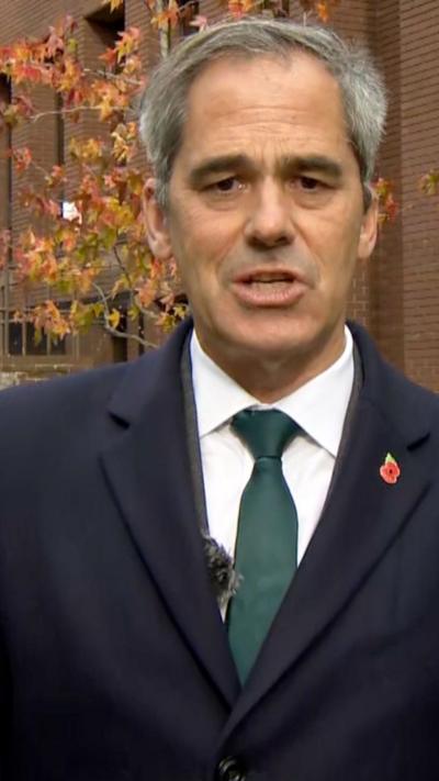 Daniel Sandford outside court. He is wearing a suit and a memorial poppy pin.