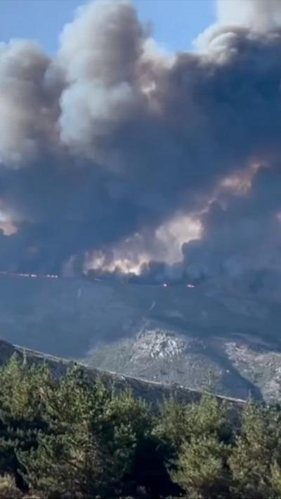 Thick smoke rises above a forest fire in Spain