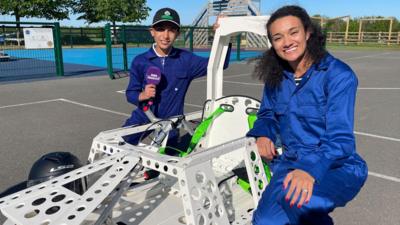 Child contributor Arun and Nina Blissett sitting with an electric car between them.