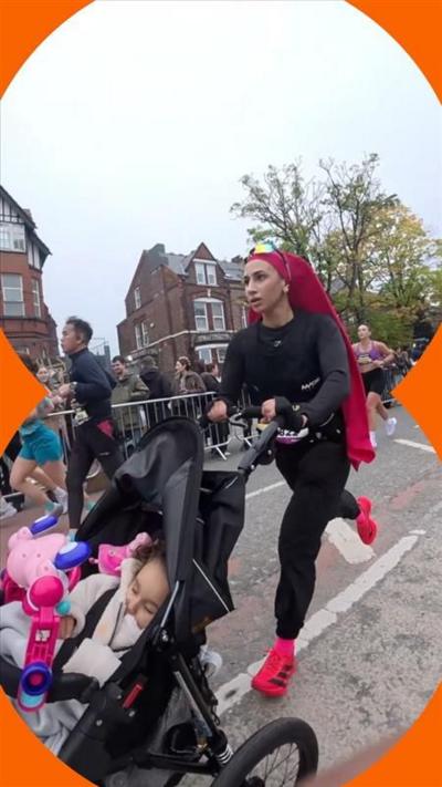 Aneila Afsar runs while pushing her daughter in a pram. She wears a black tracksuit with red headscarf and trainers