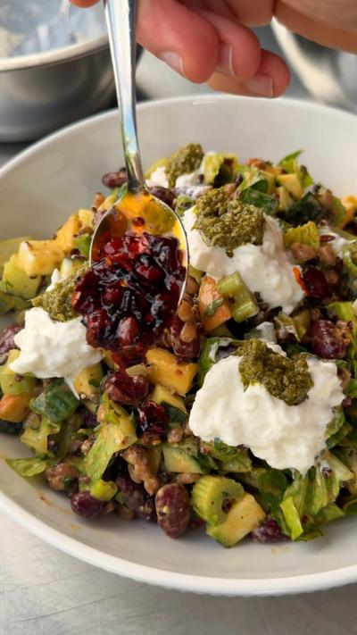 Chopped salad with cheat's straciatella in a bowl with a spoon on it 