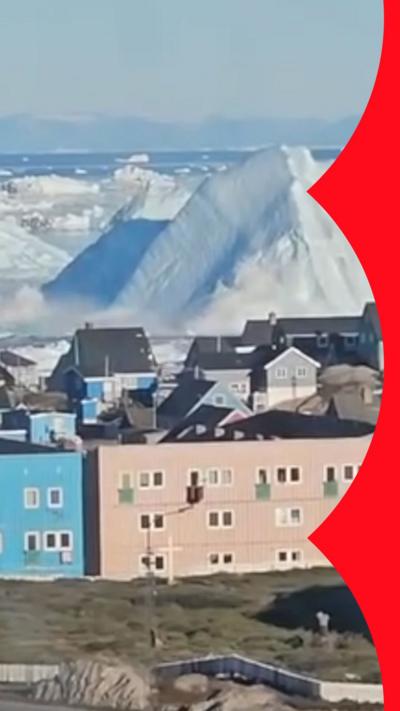 Massive iceberg towers over a small coastal town