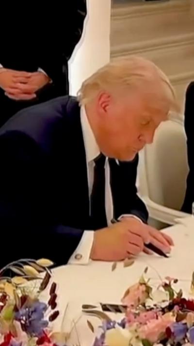 US President Donald Trump holding black pen and signing document