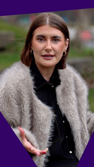 Young woman with shoulder length dark hair and white fluffy jacket.