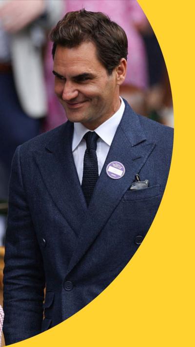 Roger Federer stands smiling. He has short brown hair and wears a dark blue suit 