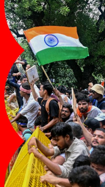 A group of protesters waving the Indian national flag in front of yellow barricades.