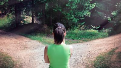 Image of a person at a fork in a woodland path