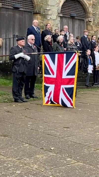 A man holding a Union flag observes a two-minute silence