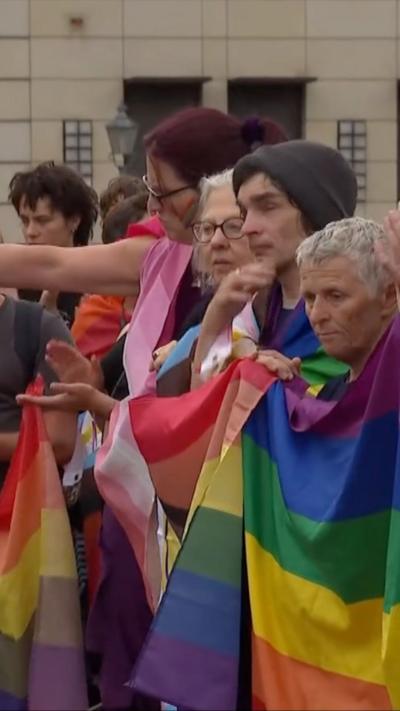A group of people standing and holding several rainbow flags.