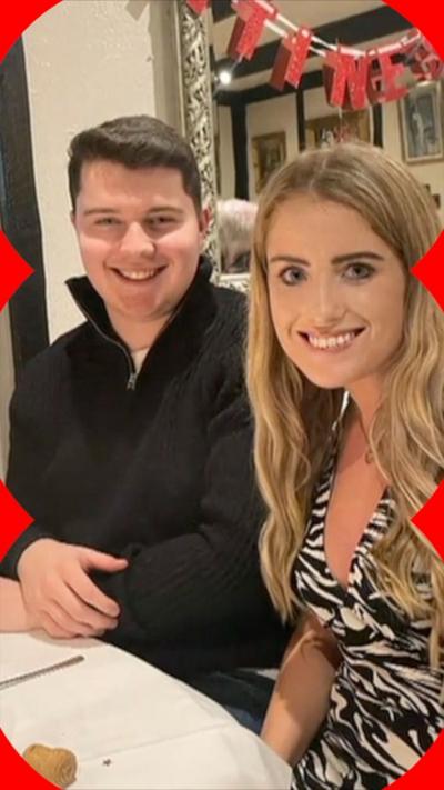 Two people, a man and a woman, sit next to each other smiling at the camera