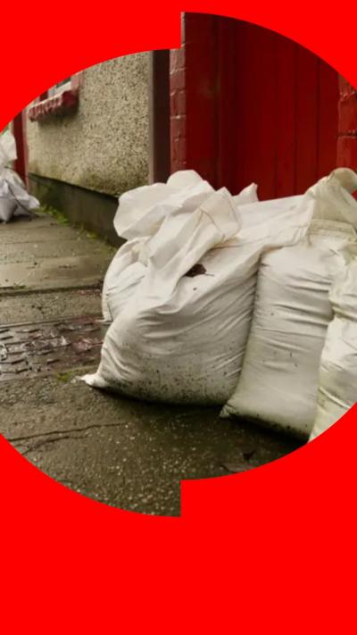 Sandbags on the street outside a red door 