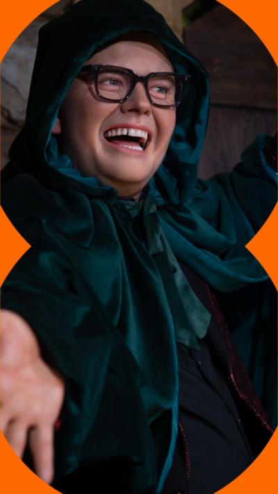 A man wearing a Traitors cloak smiles at someone off camera.