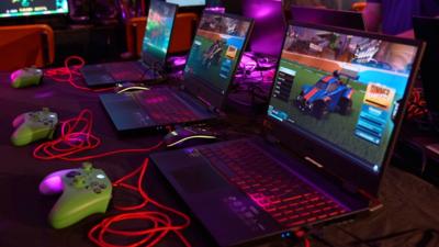 Games consoles and laptops in a row on a table