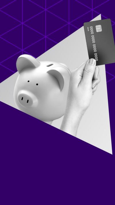 A hand holding a credit card next to a piggy bank 