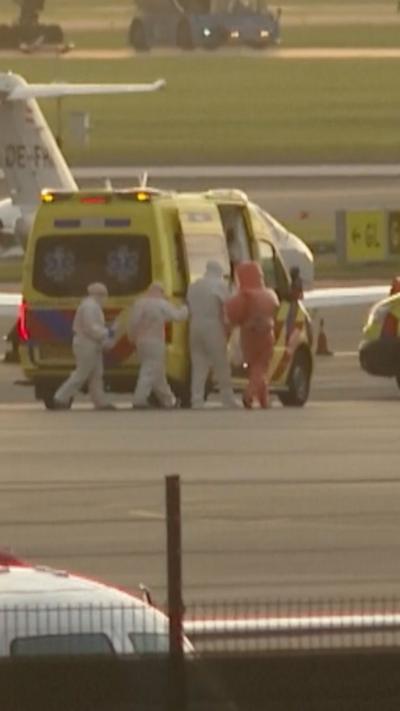 People wearing PPE walk towards an ambulance on tarmac