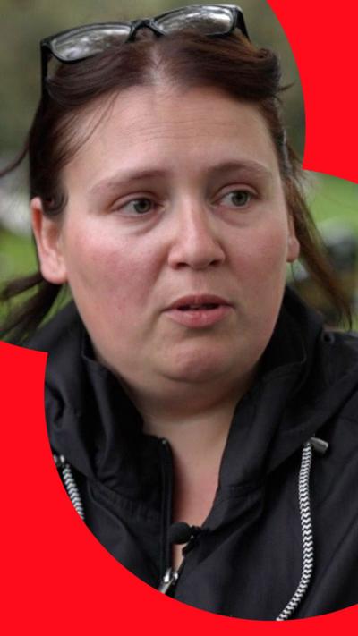 Women with dark hair wearing a black jacket interviewed at cemetery