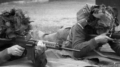 Two soldier lie on the ground, aiming their guns