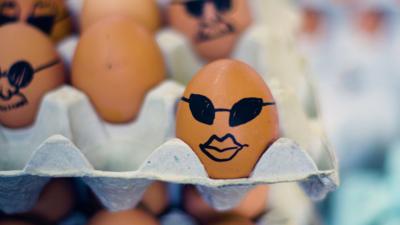 A box of chicken eggs with sunglasses and lips drawn on them