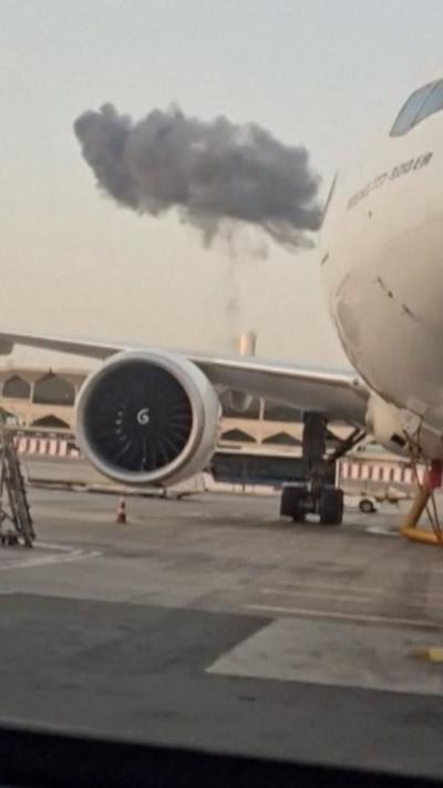 Cloud of smoke rises near airport terminal - a plane can be seen in the foreground 