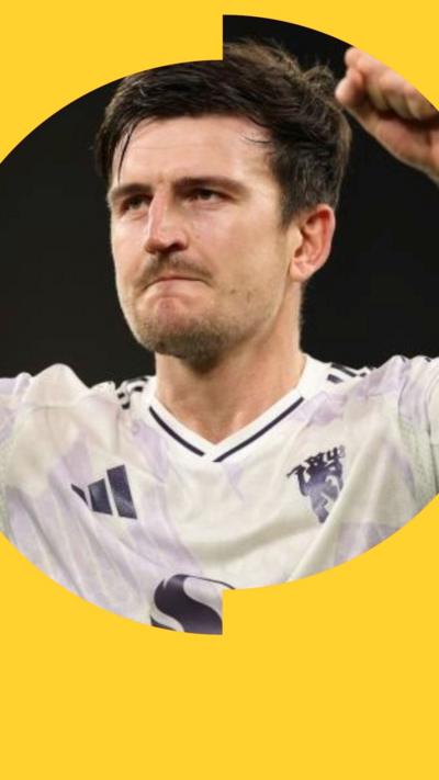 Harry Maguire, in a white football shirt, raises a fist in celebration