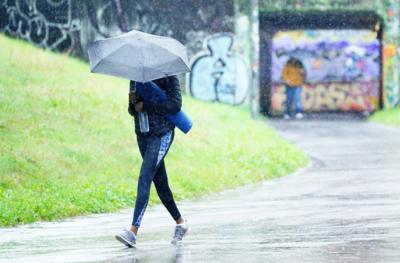 A woman walks in heavy rain in Bristol with an umbrella obscuring her face