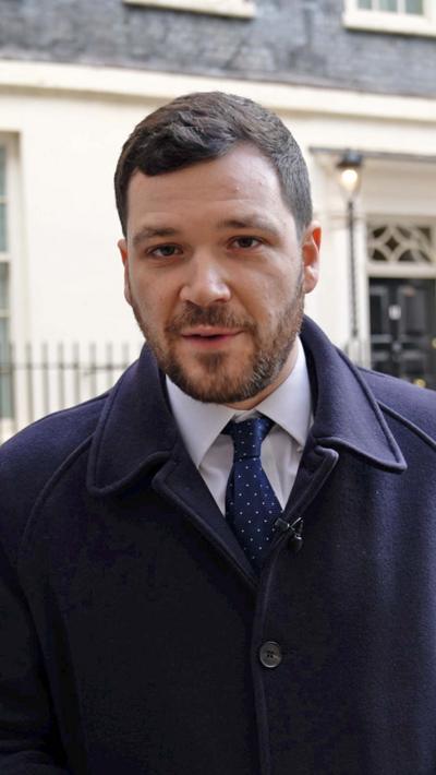 Henry Zeffman wearing a navy wool coat and blue and white spot tie