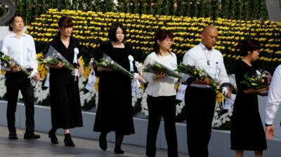 Attendees offer flowers during the Peace Memorial Ceremony on the 80th anniversary of the atomic bombing of Hiroshima