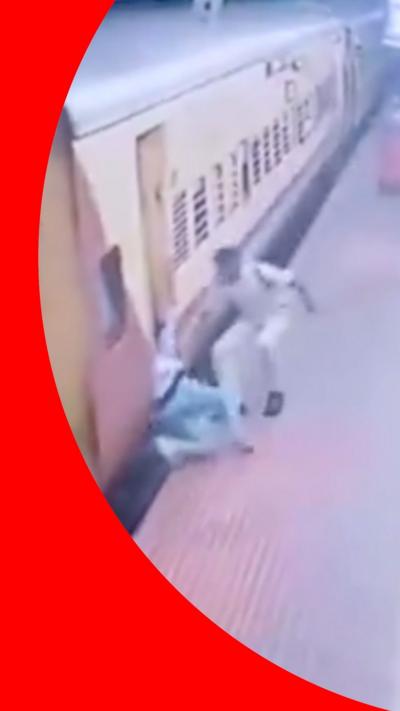 A policeman with his arm reaching towards a woman, who slipped while trying to board a moving train.