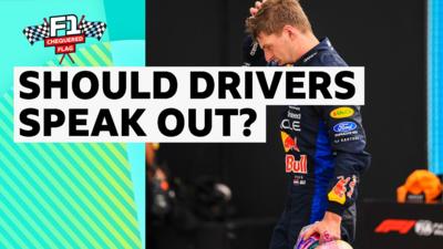 Max Verstappen dressed in Red Bull race suit with a hand to his head 
