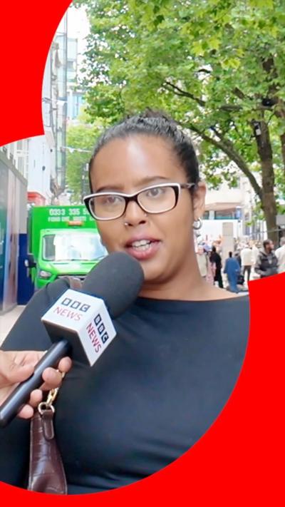 A woman with glasses and a black top speaks into a BBC News microphone.
