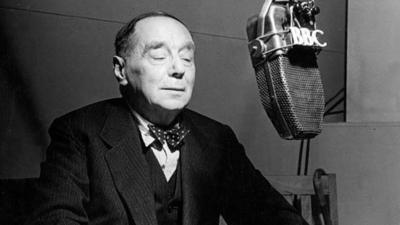 HG Wells sits in a studio behind a BBC microphone.