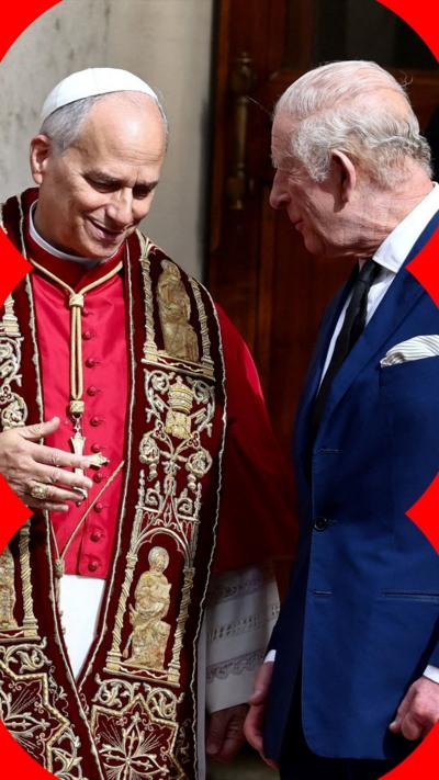 Britain's King Charles, wearing a suit, speaks with Pope Leo XIV, wearing red and gold robes.