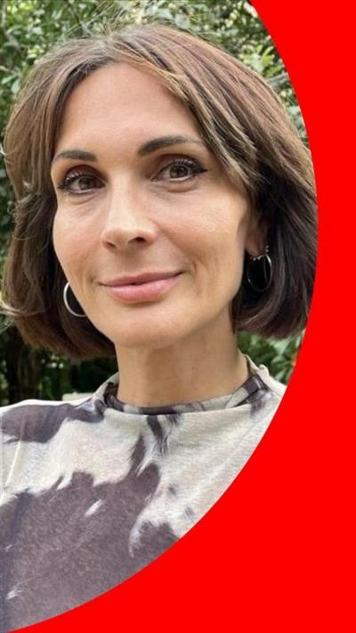 Milly stands in the gardens of the Trinity Centre. She has short dark-brown hair and wears black and white short-sleeved top.