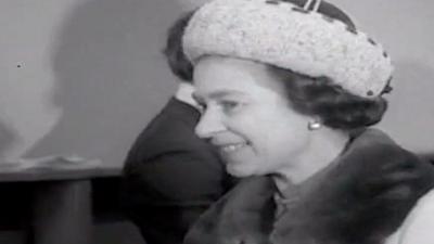 A black and white image of Queen Elizabeth. She is wearing a fur coat and hat. 