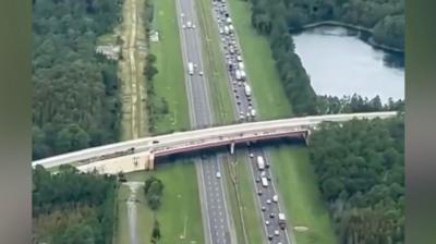 Huge queue of cars on right side of highway passing under bridge