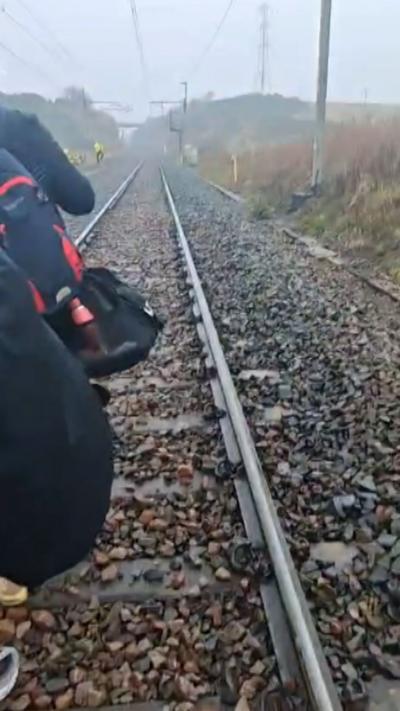 Passengers walk on the track after Glasgow-London train derailment
