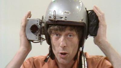 John Noakes demonstrating a helmet with a camera mounted to the side