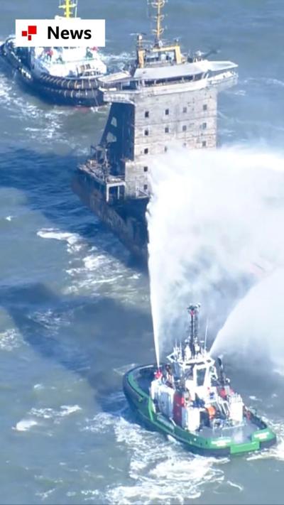 Smaller boats spraying water at the charred Solong