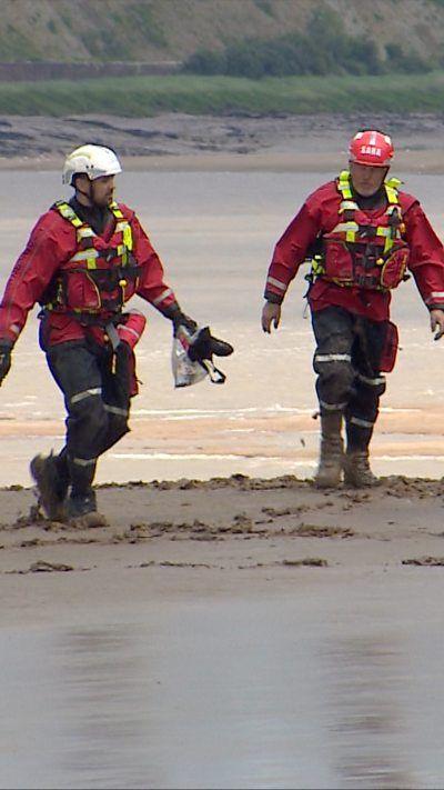 Severn Rescue team in red jackets walking through sand.