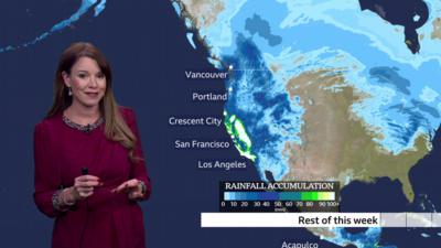 BBC Weather Presenter Elizabeth Rizzini in front of a map showing rainfall accumulation across west coast of US for the rest of this week