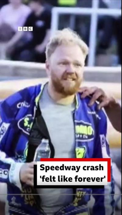 Rider Cameron Heeps walking away after the crash. His team are surrounding him. He is holding a bottle of water.